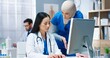 © VAKSMANV - Close up of multi-ethnic healthcare workers working and talking in hospital. Asian young female doctor typing on computer and consulting with Arab woman nurse. Medical center concept