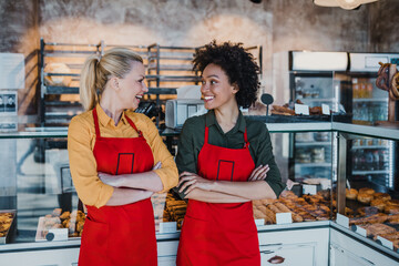 Beautiful African American and Caucasian female workers working in bakery.