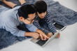 © khwanchai - Dad and young boy kid laying and looking on laptop learning online and stay at home concept
