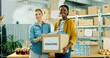 Young mixed-race happy warehouse workers volunteers working in shipping delivery charitable stock organization packing donations box looking at camera with smile on face volunteering concept