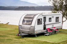 RV Caravan Camping At The Caravan Park On The Lake With Mountains On The Horizon. Camping Vacation Travel Concept