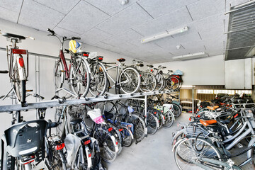 Many bikes placed on rack and floor in storage room of contemporary apartment building