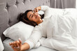 © Prostock-studio - Happy young African American woman stretching after waking up