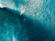 Aerial view of surfers in tropical blue ocean with waves at Bali. Top view