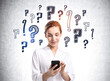 © ImageFlow - Businesswoman with phone in hands, question marks sketch