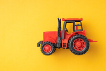 Red Toy Tractor On A Yellow Background, Banner.