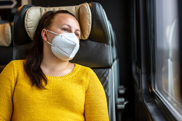 Pretty young woman with face mask also a respirator travelling by the train during pandemic covid-19, coronavirus, transport concept