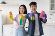 © Prostock-studio - Cheerful asian couple with supplies for cleaning posing in kitchen