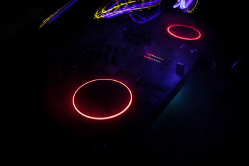 Wall Mural - DJ console deejay-mixing desk in dark with colorful light. Mixer equipment entertainment DJ station.