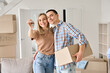 © insta_photos - Happy young couple home owners holding keys in new home. Smiling independent millennial man and woman first time homeowners carrying boxes on moving day. Mortgage loan, new house ownership concept.