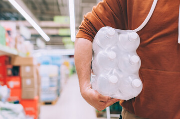 Wall Mural - A man in a store holds a package of clean and transparent bottled water.