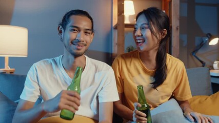 Wall Mural - Happy young asian couple looking at camera enjoy night party event online sit couch video call with friends toast drink beer via video call online in living room at home, Social distancing concept.