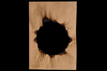 Vintage paper with a burned round hole in the middle with black background. Isolated on black. 
