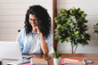 © InsideCreativeHouse - Confident african young businesswoman working on her laptop in office. Happy mixed race pretty woman student looking at computer screen watching webinar or doing video chat by webcam.