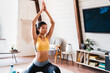 © InsideCreativeHouse - Young african sporty slim woman practicing yoga indoors. Sport, fitness and healthy lifestyle concept - happy young african american woman stretching legs at home with her arms up