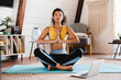 © InsideCreativeHouse - Serene young fit african woman meditating at home using laptop. Home Training. Relaxed woman in practicing online sports, watching video tutorial on laptop computer, doing stretching yoga exercises