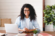 © InsideCreativeHouse - Successful young afro businesswoman working at her office desk. Front view of smiling african american female freelancer working at home