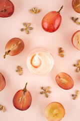 Wall Mural - Concept organic extract nature grape seeds oil in cream for skin care in home. Creative modern flat lay composition with fresh red grapes and seeds in pink background. Naturecore. Eco. Close up