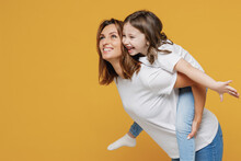 Happy Woman In White T-shirt Have Fun With Cute Child Baby Girl 5-6 Years Old Sit On Back. Mommy Little Kid Daughter Isolated On Yellow Orange Color Background Studio Mother's Day Love Family Concept