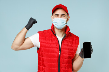 Wall Mural - Delivery guy employee man in red cap white t-shirt vest uniform sterile face mask gloves work courier service on lockdown coronavirus flu hold use mobile cell phone isolated on pastel blue background.