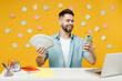 Young successful employee business man in shirt sit work at white office desk with pc laptop hold mobile cell phone holding fan of cash money in dollar banknotes isolated on yellow background studio.