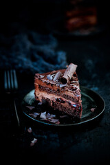 Plate with slice of tasty homemade chocolate cake on a dark background