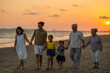 Happy big Asian family on beach holiday vacation. Multi-generation family holding hands and walking together on tropical beach at summer sunset. Family enjoy and having fun outdoor activity lifestyle.
