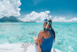 Snorkeling from boat in Bora Bora, Tahiti, French Polynesia. Woman jumping in crystal clear water with snorkel gear in coral reef lagoon with Bora Bora landmark Mount Otemanu in background