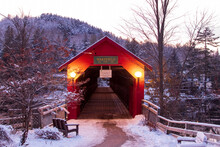 Red Covered Bridge In Winter With Snow-covered Trees On The Hillside