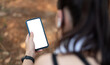 © Natee Meepian - Young sporty woman holding mobile phone with blank screen indoors, closeup view. Mockup for design.