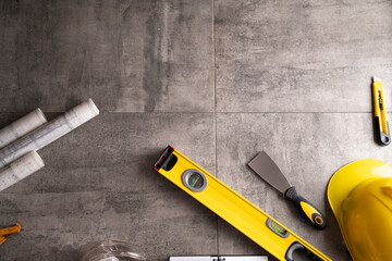 Contractor theme. Tool kit of the contractor: yellow hardhat, libella and tools on the gray tiles background.