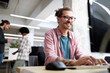 © NDABCREATIVITY - Young hipster man smiling while working on computer desk in office