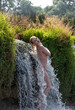 Beautiful young nude woman enjoying summertime in waterfall