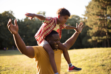 Wall Mural - Shoulders ride.  African American father and son in nature.