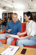 © DragonImages - Young entrepreneurs sitting at table in office cafeteria and discussing business documents and report