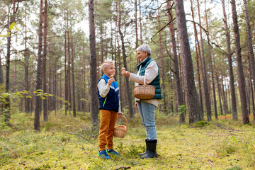 Canvas Print - picking season, leisure and people concept - happy smiling grandmother and grandson with baskets and mushrooms in forest