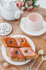 Wall Mural - Close-up of baklava. Turkish Ramadan Arabic sweet dessert on a decorative plate, with a coffee cup in the background. Middle Eastern food baklava with nuts and honey syrup.