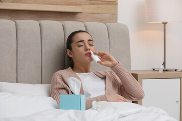 Canvas Print - Sick young woman using nasal spray in bed at home