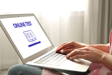 Wall Mural - Woman using laptop for online test indoors, closeup