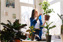 Young Woman Florist Taking Care Of Pot Plants