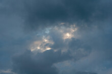 Covered With Dark Blue Clouds With Small Gap Through Which Sun's Rays And Bright Blue Sky Break Through.