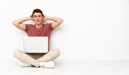 Poster - Teenager man sitting on the flor with his laptop frustrated and takes hands on head