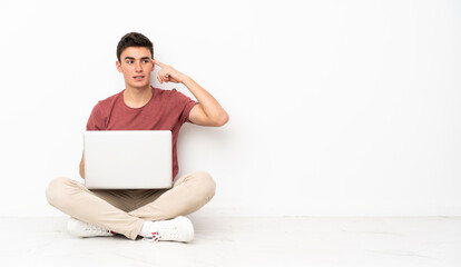 Poster - Teenager man sitting on the flor with his laptop making the gesture of madness putting finger on the head