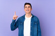 © luismolinero - Teenager caucasian  handsome man isolated on purple background thinking an idea pointing the finger up
