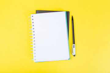 Wall Mural - open spiral notepad on a yellow background with a pen. top view, stack of notepad with blank sheet. school concept, businessman work