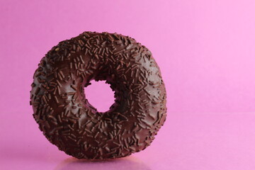 Wall Mural - Chocolate berliner doughnut on a pink background with a place to text a copyspace breakfast dessert national dish