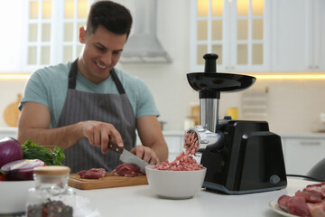 Canvas Print - Man cutting meat in kitchen, focus on modern grinder