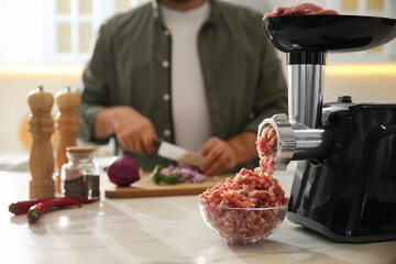 Canvas Print - Closeup view of man cutting onion in kitchen, focus on meat grinder