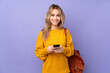 © luismolinero - Teenager Russian student girl isolated on purple background sending a message with the mobile
