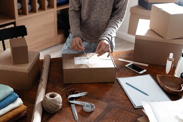 Indian mixed-race female business owner working, packing the order for shipping to customer